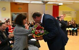 na zdjęciu widać radnego składającego bukiet emerytowanej nauczycielce plastyki