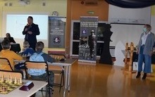 na zdjęciu widać przemawiającego Pana dyrektora podczas konkursu szachowego oraz po  lewej stronie stoją Panie vice dyrektorki