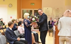 na zdjęciu widać dyrektora, kt&oacute;ry wręcza bukiet kwiat&oacute;w emerytowanym nauczycielką