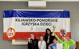 na zdjęciu widać uczni&oacute;w Szkoły Podstawowej w Łochowie, kt&oacute;rzy stoją z medalami, dyplomami i pucharami zdobytymi w igrzyskach szachowych