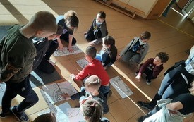 na zdjęciu widać uczestnik&oacute;w p&oacute;łkolonii rozwiązujących zagadkę w postaci dużych  puzzli