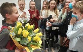 na zdjęciu widać składanie gratulacji chłopcu z ż&oacute;łtymi tulipanami