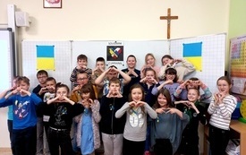 Na zdjęciu widać uczni&oacute;w klas I-III solidaryzujących się z Ukrainą, pokazujący symbol serca dłońmi