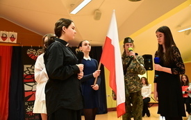 na zdjęciu widać uczni&oacute;w podczas uroczystej akademii z okazji narodowego święta niepodległości trzymających flagę Polski