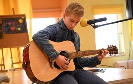 na zdjęciu widać uczestnika Szkolnego Mam Talent podczas gry  na gitarze