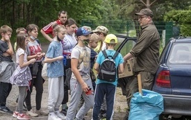 Na zdjęciu widać leśniczego rozdającego nagrody uczniom za ich wysiłek włożony w sprzątanie lasu.