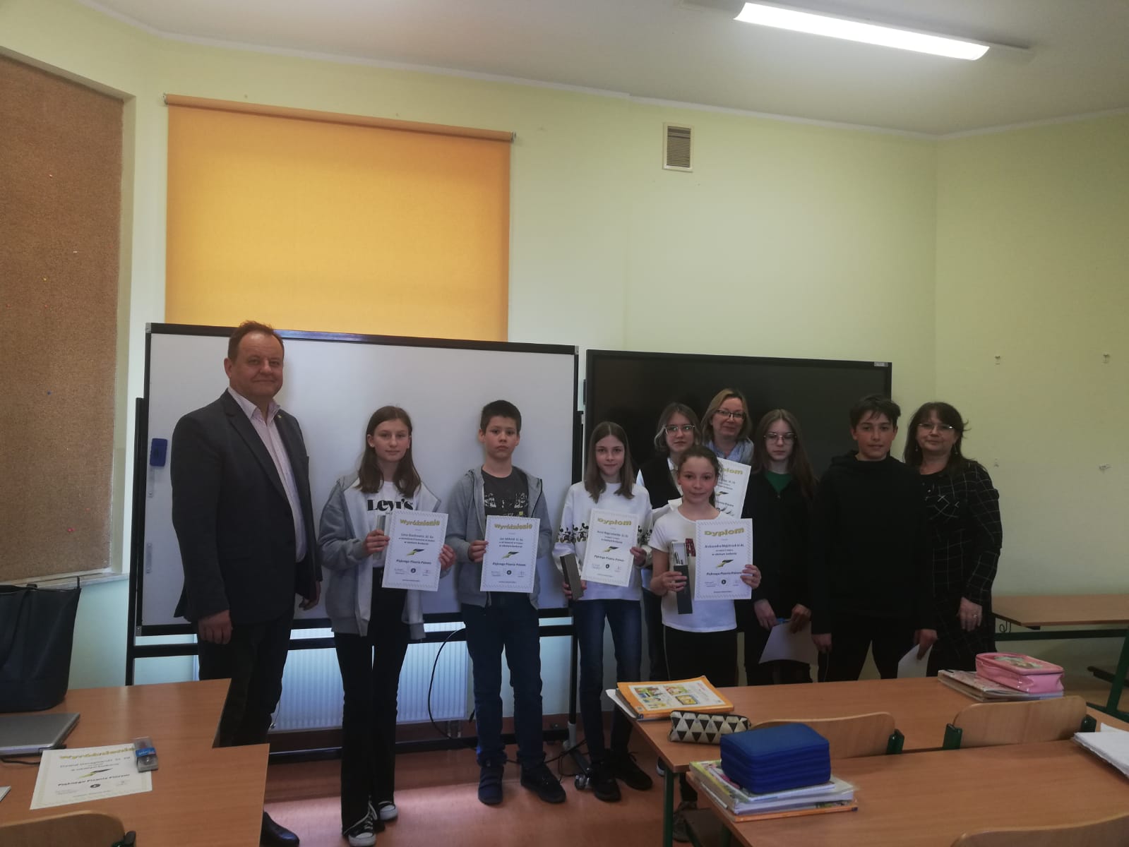 Konkurs pięknego czytania Na zdjęciu widać grupę uczniów, dyrektora szkoły oraz dwie nauczycielki pozujące w klasie do zdjęcia