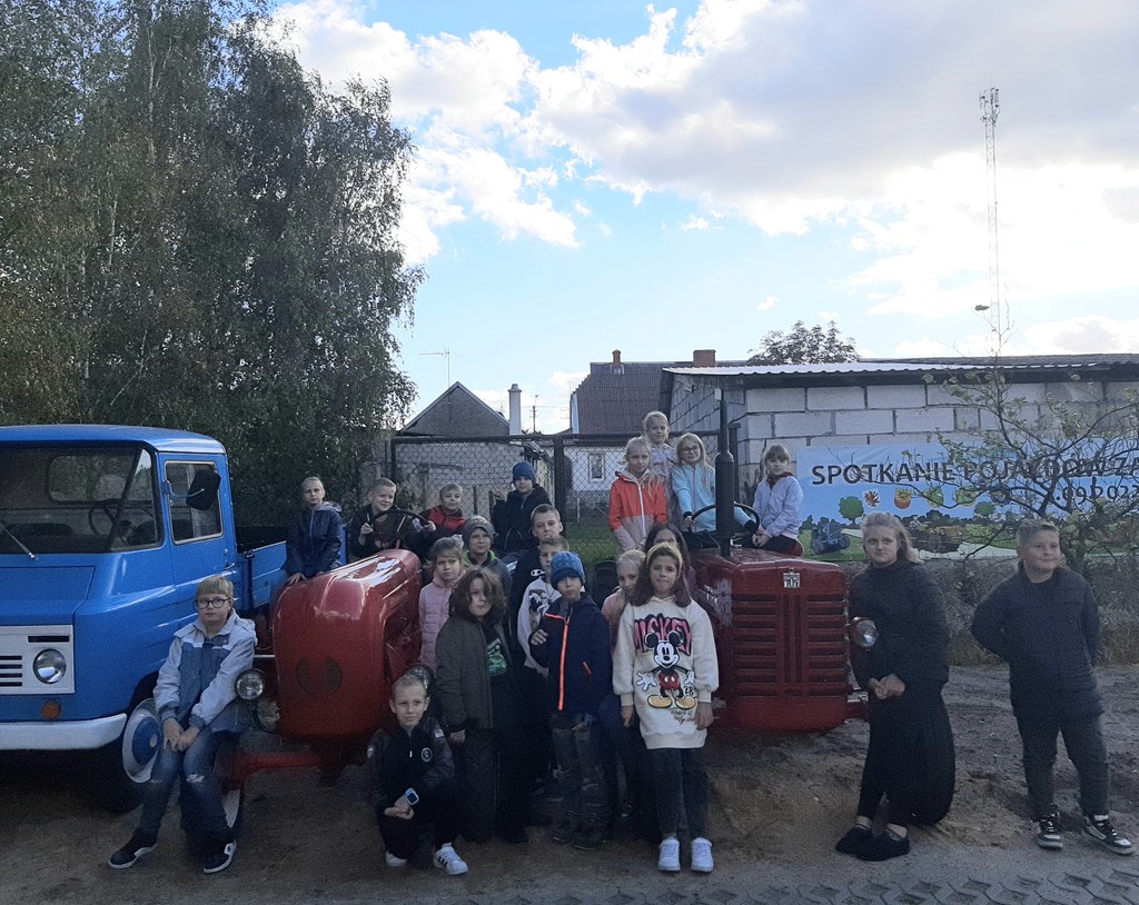 Zdjęcie przedstawia uczniów klasy 3b w Skansenie Narzędzi i Maszyn Rolniczych w Łochowicach. Dzieci stoją w grupie na tle traktora.