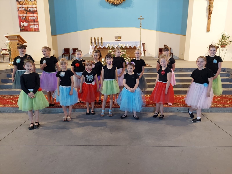 Dziewczynki z Bambino Zdjęcie przedstawia dziewczynki - skład chóru Bambino, ubrane w czarne koszulki oraz kolorowe spódnice na tle ołtarza, wewnątrz kościoła.