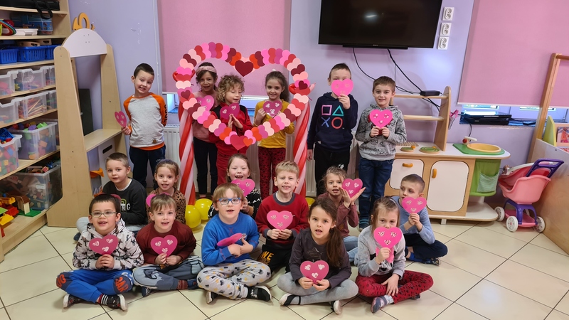 Walentynki w zerówce Zdjęcie przedstawia wychowanków oddziału przedszkolnego w grupie pozujących do zdjęcia z własnoręcznie wykonanymi walentynkami.