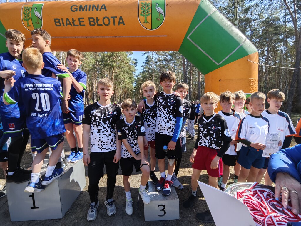 Zawodnicy w&nbsp;strojach sportowych stoją na&nbsp;podium, na&nbsp;trzecim miejscu.