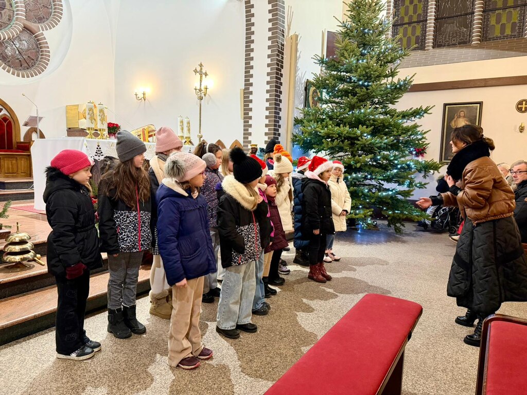 Ch&oacute;rzystki z&nbsp;ch&oacute;ru Bambino przed ołtarzem kościoła kolędują dla wiernych, przed nimi dyrygentka Lidia Kwiatkowska.