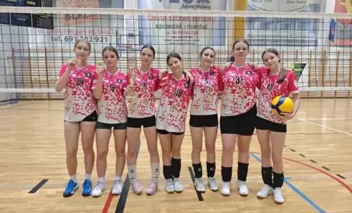 Zawodniczki drużyny siatkarskiej z SP Łochowo pozują do zdjęcia w strojach sportowych z medalami na sali gimnastycznej.