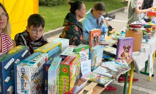 Na zdjęciu widać dwie pary wystawców, którzy oferują swoje towary m.in. książki, gry planszowe, zabawki.