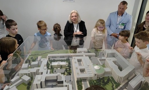 Zdjęcie przedstawia uczniów oglądających makietę przedstawiającą budynki rządowe w Warszawie oraz przewodniczkę i jednego z rodziców.
